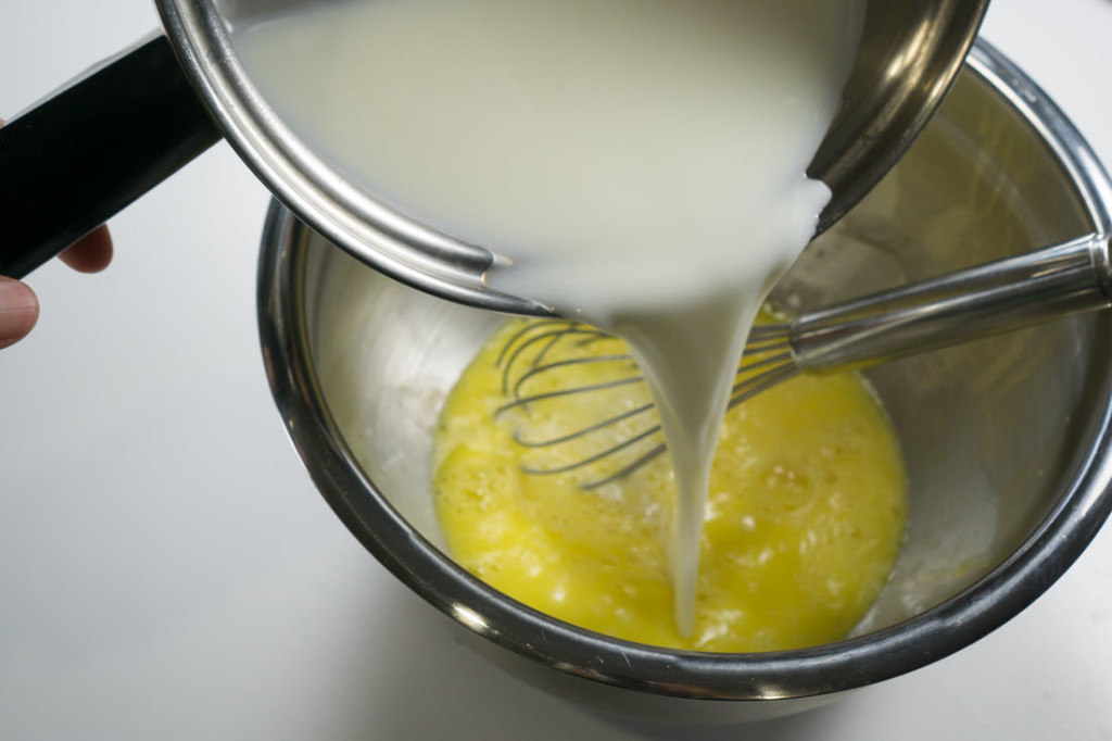 Whisking the warmed milk-sugar mixture into the whisked eggs